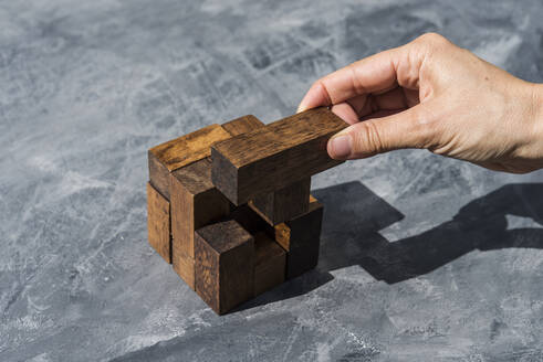 Hand einer Frau, die Teile eines Holzpuzzles zusammensetzt - SKCF00634