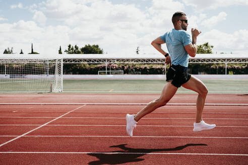 Male athlete running on tartan track - EBBF00225