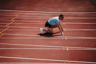 Male athlete in starting position on tartan track - EBBF00230