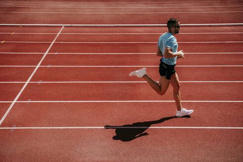 Male athlete running on tartan track - EBBF00232