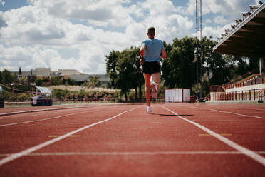 Male athlete running on tartan track - EBBF00240