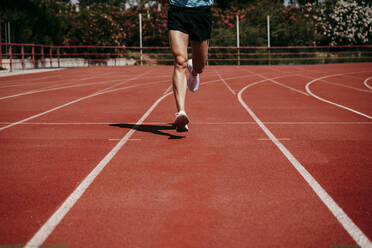 Legs of a man running on tartan track - EBBF00241