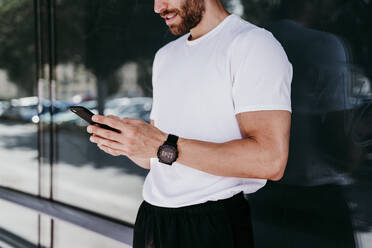 Male athlete having a break checking smartphone - EBBF00245