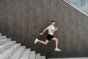 Männlicher Sportler, der eine Treppe hinunterläuft - EBBF00252