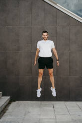 Männlicher Athlet, der vor eine Wand springt - EBBF00253