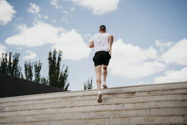 Male athlete running up stairs - EBBF00256