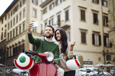 Mann macht Selfie mit seiner Freundin auf einer Vespa in der Stadt Florenz - SODF00751