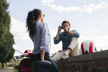 Man photographing girlfriend standing by Vespa - SODF00755