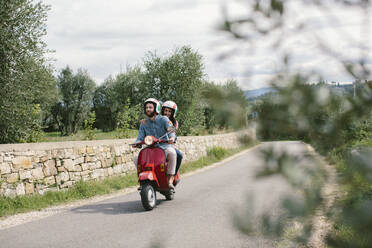 Couple enjoying road trip on Vespa, Tuscany, Italy - SODF00775