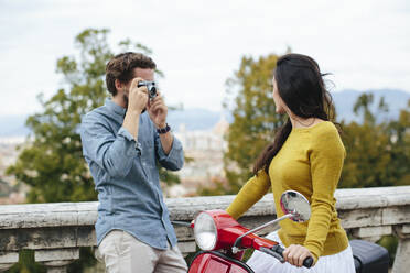 Young man photographing girlfriend sitting on Vespa - SODF00789