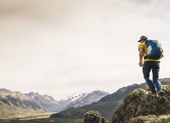 Mature hiker with backpack walking on rock against sky, Patagonia, Argentina - UUF20675