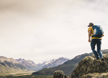 Älterer Wanderer mit Rucksack, der auf einem Felsen gegen den Himmel läuft, Patagonien, Argentinien - UUF20675