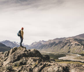 Älterer Mann mit Rucksack auf einem Felsen stehend gegen den Himmel, Patagonien, Argentinien - UUF20676