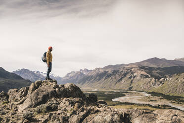 Älterer Mann mit Rucksack steht auf einem Felsen gegen den Himmel in Patagonien, Argentinien - UUF20677