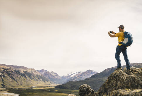 Älterer Mann fotografiert Berge mit Smartphone gegen den Himmel, Patagonien, Argentinien - UUF20678