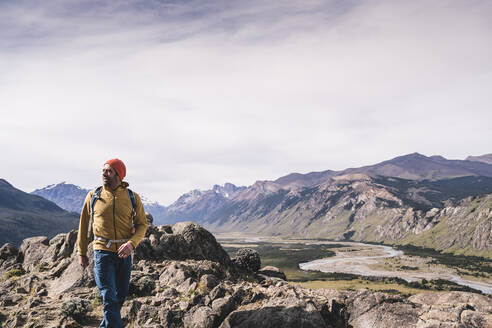 Männlicher Wanderer, der in Patagonien, Argentinien, auf Felsen gegen Berge läuft - UUF20685