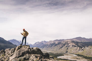 Pensive hiker using smart phone on mountain peak during sunrise at Bergamasque  Alps, Italy stock photo