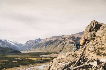 Männlicher Wanderer entspannt sich auf einem Felsen gegen den Himmel, Patagonien, Argentinien - UUF20691