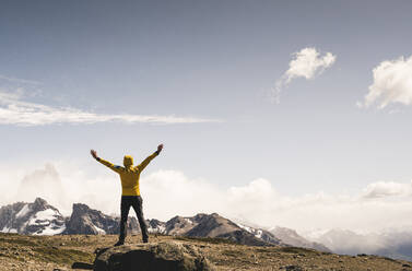 Man with arms outstretched looking at landscape against sky, Patagonia, Argentina - UUF20709