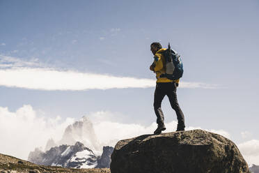 Männlicher Wanderer mit Rucksack auf einem Felsen stehend gegen den Himmel an einem sonnigen Tag, Patagonien, Argentinien - UUF20712