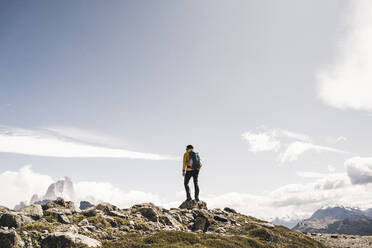 Wanderer mit Rucksack auf einem Berg stehend gegen den Himmel an einem sonnigen Tag, Patagonien, Argentinien - UUF20716