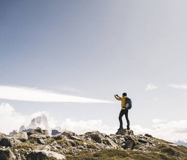 Mann beim Fotografieren auf einem Berg stehend gegen den Himmel an einem sonnigen Tag, Patagonien, Argentinien - UUF20717