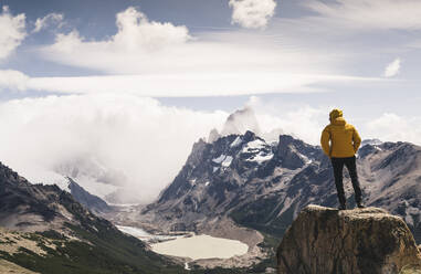 Mann schaut auf einen schneebedeckten Berg vor bewölktem Himmel, Patagonien, Argentinien - UUF20722