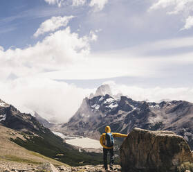 Man with backpack looking at snowcapped mountain against sky, Patagonia, Argentina - UUF20727