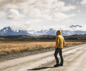 Mann auf unbefestigter Straße vor bewölktem Himmel im Torres Del Paine National Park, Patagonien, Chile - UUF20733