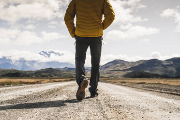 Niedriger Ausschnitt eines erwachsenen Mannes, der auf einer unbefestigten Straße im Torres Del Paine National Park, Patagonien, Chile, geht - UUF20736