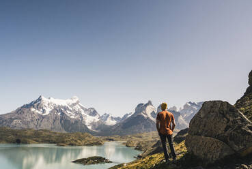 Mature man standing by lake against clear sky at Torres Del Paine National Park, Patagonia, Chile - UUF20739