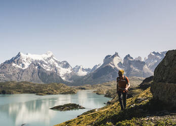 Man walking by lake against clear sky, Torres Del Paine National Park, Patagonia, Chile - UUF20744