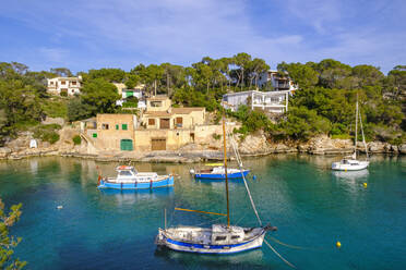 Spain, Mallorca, Santanyi, Fishing boats moored in front of coastal village in summer - SIEF09935