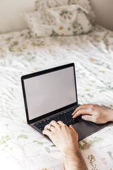 Mann mit Laptop auf dem Bett - FLMF00262