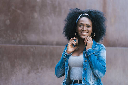 Smiling woman with afro hair and headphones looking at camera - JAF00004