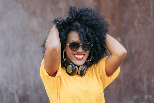 Smiling woman with afro hair and sunglasses and hands in hair - JAF00006