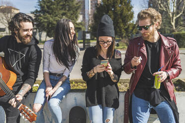 Mid adult woman using smart phone while standing with friends in city - MEUF00991