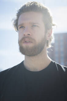 Close-up of thoughtful bearded man looking away against sky during sunny day - MEUF01009