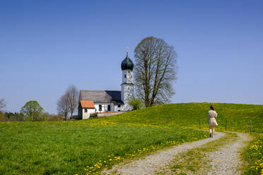 Deutschland, Bayern, Bad Heilbrunn, Teenager-Mädchen geht auf einem Feldweg in Richtung Marienkirche - LBF03096