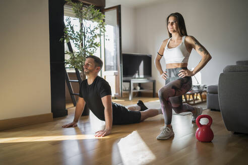 Couple exercising on floor in living room at home - MTBF00483