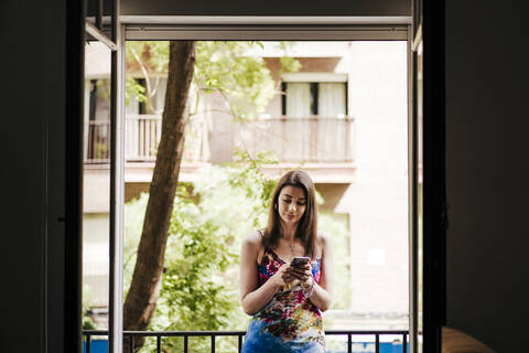 Woman using phone while standing in balcony stock photo