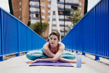 Frau übt Yoga-Haltung auf einer Brücke - EBBF00317