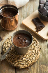 Close up of a cup of hot chocolate with chocolate chunks topping on a wood surface - ADSF00010