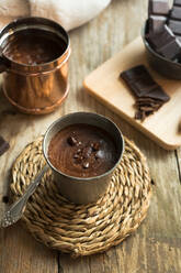 Nahaufnahme einer Tasse heißer Schokolade mit Schokostückchen als Topping auf einer Holzoberfläche - ADSF00010