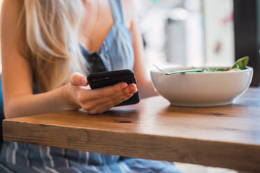 Woman browsing smartphone in cafe - ADSF00082