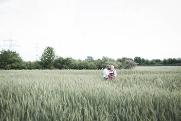 Reifes Paar, das sich küsst, während es inmitten von Pflanzen in einer Landschaft mit klarem Himmel steht - HMEF00975