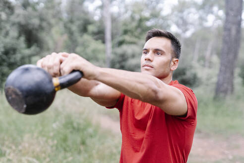 Young athletic man with dumbbell in the woods - JCZF00175