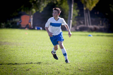 Jugendlicher Fußballspieler, der auf einem Fußballfeld läuft - CAVF86213