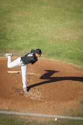 Teenager-Baseballspieler in schwarz-weißer Uniform in voller Montur auf dem Mound - CAVF86217