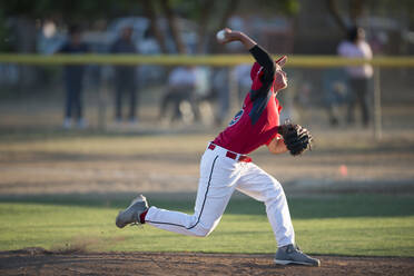 Teenager-Baseballspieler in roter Uniform beim Aufwärmen auf dem Hügel - CAVF86219